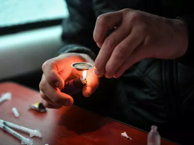 A drug user prepares and injects heroine inside former drug user-turned-drug policy campaigner Peter Krykant's "Safe Consumption" van, a mobile sterile drugs consumption facility he runs, in Glasgow on September 11, 2020. In the shade of the buildings at the bottom end of a secluded street in central Glasgow, Peter Krykant gets out of his converted white minibus and glances up an adjacent alleyway. Drug spoons, bloody syringes and human excrement litter the ground. Krykant, 43, knows these streets well. Before he gave up drugs 11 years ago, he was homeless and would inject cocaine and heroin in places just like these.,Image: 559114412, License: Rights-managed, Restrictions: TO GO WITH AFP STORY by Stuart GRAHAM, Model Release: no