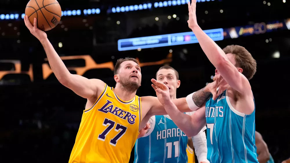 Los Angeles Lakers guard Luka Doncic, left, shoots as Charlotte Hornets center Ryan Kalkbrenner, center, and guard Kon Knueppel defend during the first half of an NBA basketball game Thursday, Jan. 15, 2026, in Los Angeles. (AP Photo/Mark J. Terrill)