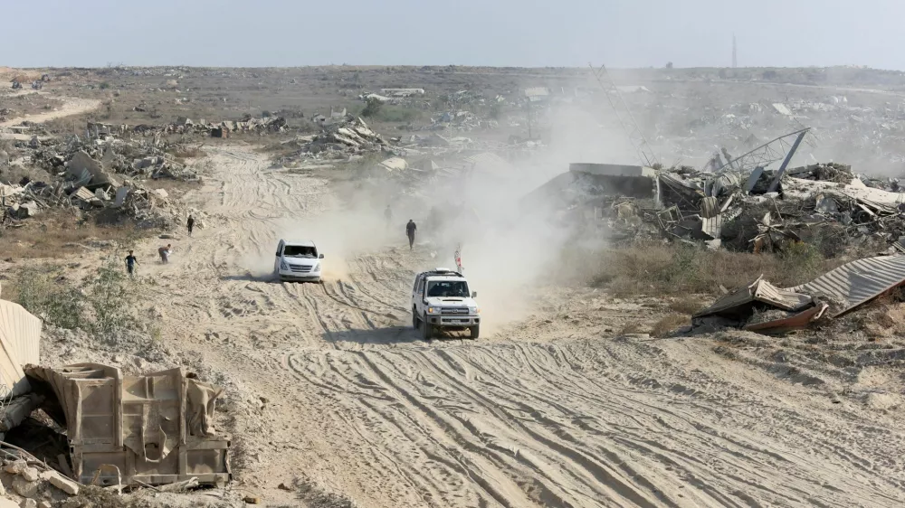 A Red Cross vehicle, escorted by a van driven by a Hamas militant, moves in an area within the so-called "yellow line" to which Israeli troops withdrew under the ceasefire, as Hamas says it continues to search for the bodies of deceased hostages seized during the October 7, 2023, attack on Israel, in Gaza City November 12, 2025. REUTERS/Dawoud Abu Alk