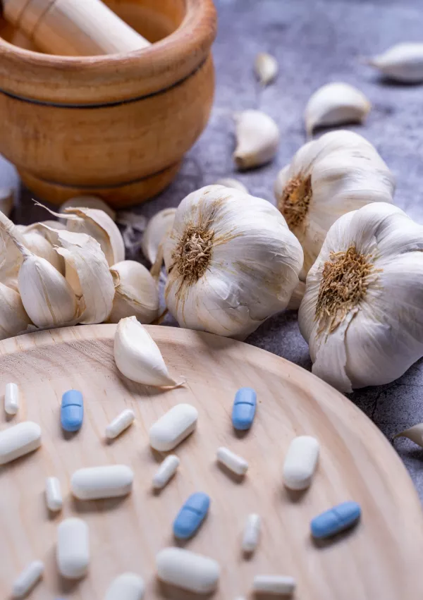 A closeup of pills on a wooden plate and garlic on the si / Foto: Wirestock