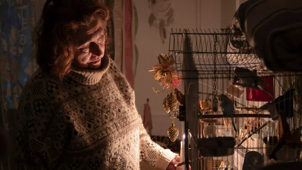 Tetyana Tatarenkova stands with a candle near a cage with ploughs during a power outage caused by regular Russian air strikes on the country's energy facilities in Kyiv, Ukraine, Tuesday, Jan. 13, 2026. (AP Photo/Dan Bashakov)