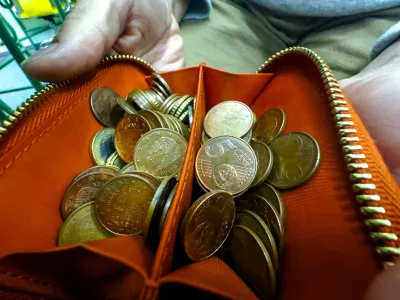 Close-up view of an unzipped orange wallet brimming with assorted euro cent coins, symbolizing budgeting, savings, and small change handling. / Foto: Pavel Samsonov, Getty Images