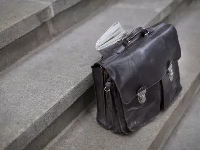 Brown briefcase waiting on the steps of an Office Tower Building. / Foto: Chuckstryker Getty Images/istockphoto
