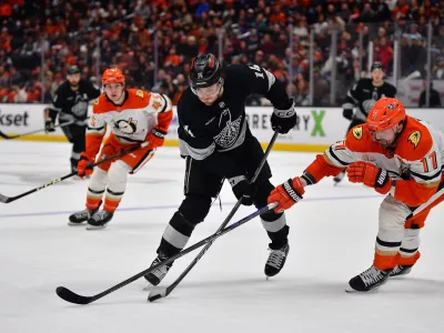 Jan 17, 2026; Anaheim, California, USA; Los Angeles Kings right wing Alex Laferriere (14) moves the puck against Anaheim Ducks left wing Alex Killorn (17) during the third period at Honda Center. Mandatory Credit: Gary A. Vasquez-Imagn Images