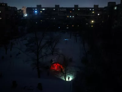 A person carrying a torch approaches a tent provided by emergency services for residents whose apartments are left without heating during sub-zero temperatures, amid Russia's attack on Ukraine, during a winter night in Kyiv, Ukraine, January 17, 2026. REUTERS/Thomas Peter    TPX IMAGES OF THE DAY