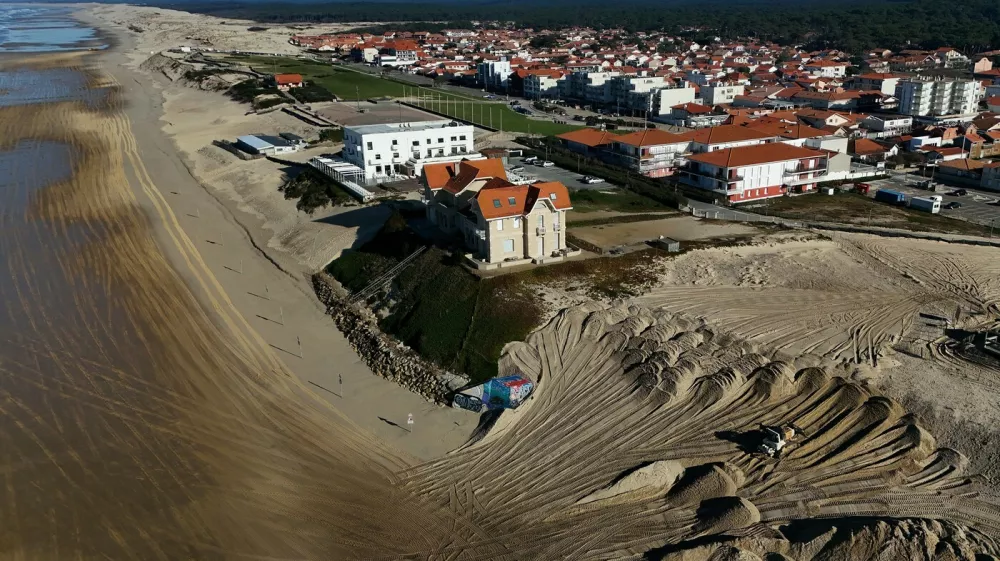 This aerial picture shows a mechanical excavator using sand brought by trucks from the northern dune cord outside the city, to reinforce the dune beside twin early 20th century villas (C) and a hotel, threatened by marine erosion, in Biscarosse southwestern France on January 17, 2025.,Image: 955698814, License: Rights-managed, Restrictions:, Model Release: no