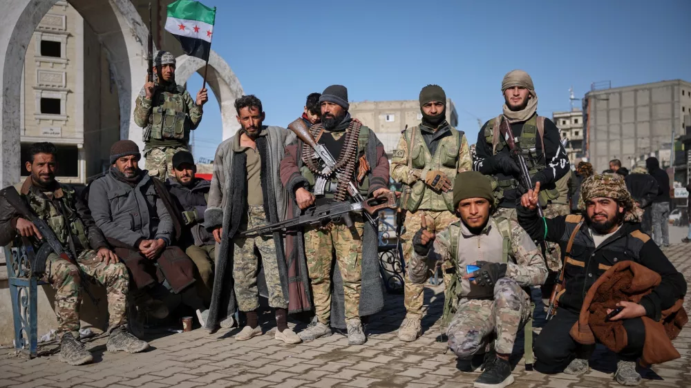 Tribal fighters pose for photographs taken by onlookers after Syrian government troops, supported by allied tribal forces, took control of Raqqa from the Syrian Democratic Forces (SDF) last Sunday at Al-Naeem roundabout in central Raqqa, northeastern Syria, Tuesday, Jan. 20, 2026. (AP Photo/Ghaith Alsayed)