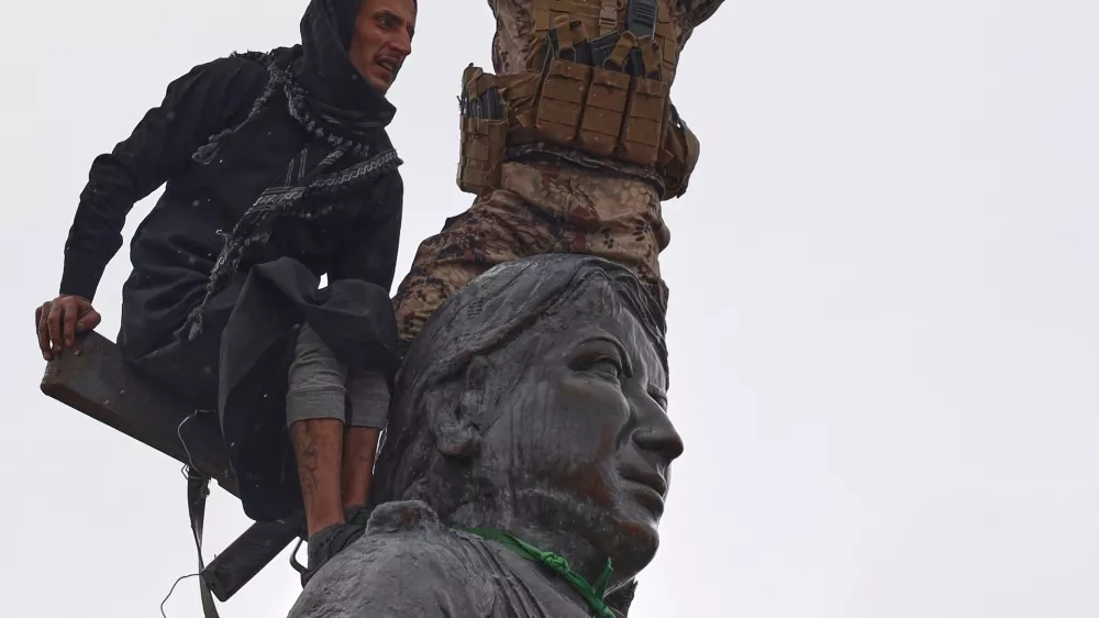 FILE - Syrian government soldiers wave a Syrian flag after climbing atop a statue of a female Kurdish fighter, following the takeover of the town from U.S.-backed Syrian Democratic Forces (SDF) during an ongoing push against Kurdish-led forces, in Tabqa, eastern Syria, Jan. 18, 2026. (AP Photo/Omar Albam, File)