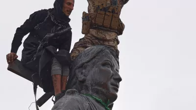 FILE - Syrian government soldiers wave a Syrian flag after climbing atop a statue of a female Kurdish fighter, following the takeover of the town from U.S.-backed Syrian Democratic Forces (SDF) during an ongoing push against Kurdish-led forces, in Tabqa, eastern Syria, Jan. 18, 2026. (AP Photo/Omar Albam, File)