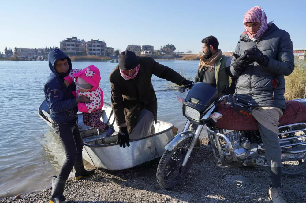 A man gets out of a boat near a damaged bridge, that according to Syrian army was destroyed by the Kurdish-led Syrian Democratic Forces (SDF) in Raqqa, Syria, January 20, 2026. REUTERS/Karam al-Masri