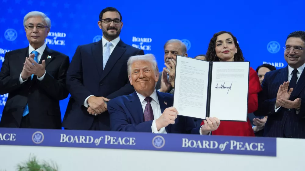 President Donald Trump, center, holds up a signed Board of Peace charter during the Annual Meeting of the World Economic Forum in Davos, Switzerland, Thursday, Jan. 22, 2026. (AP Photo/Evan Vucci)