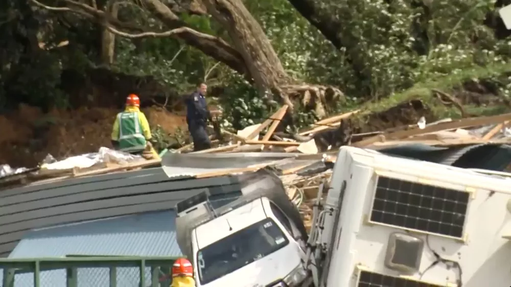 In this image from a video, a police officer with dog searches people near the site of a landslide at the base of Mount Maunganui on New Zealand's North Island Thursday, Jan. 22, 2026. (TVNZ via AP)