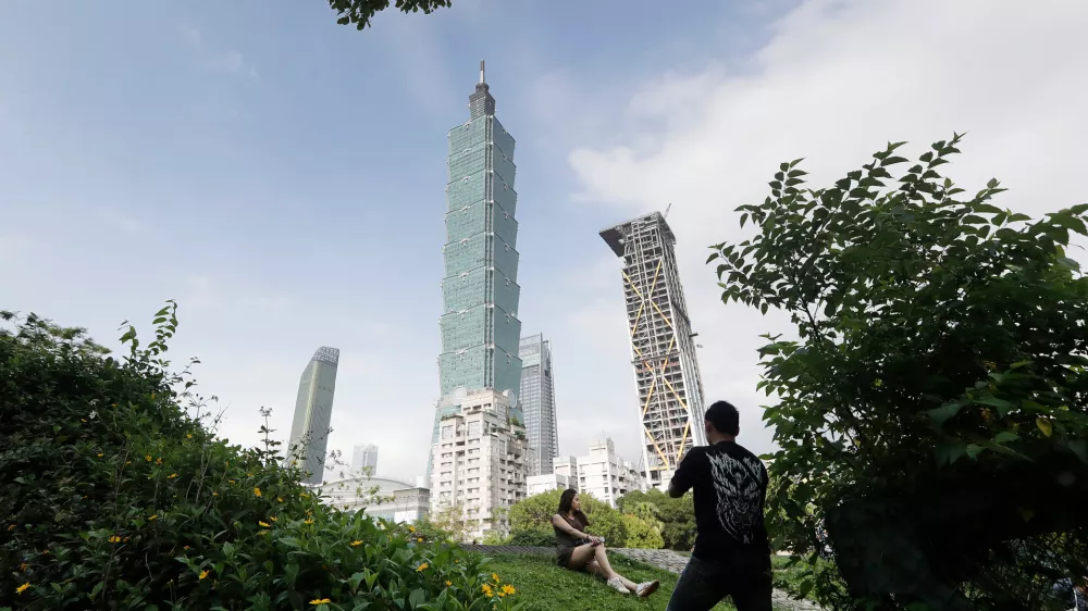 FILE - People take photos with the iconic Taipei 101 skyscraper in the background in Taipei, Taiwan, April 27, 2025. (AP Photo/Chiang Ying-ying, File)
