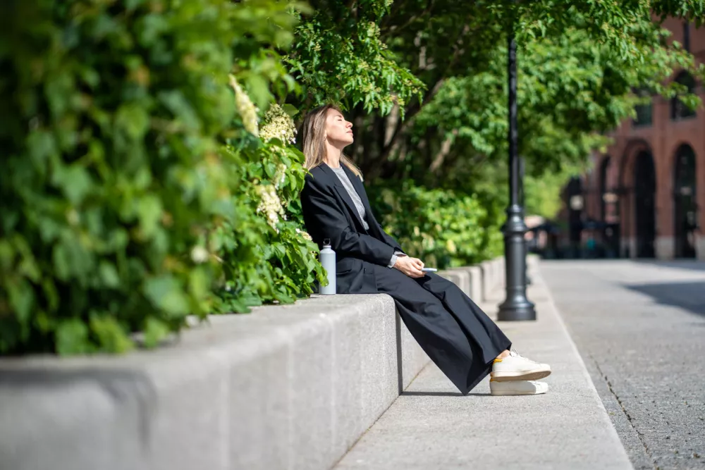 Satisfied woman warms on sun outdoor with eyes closed, enjoy time alone in break. Businesswoman resting finish work day walking in park, feeling calm pleasure, stress relieve distracted from business.