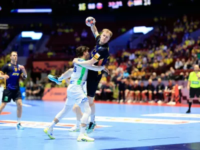 Slovenia's Domen Makuc tries to stop Sweden's Eric Johansson, top, during the European Championship handball match between Slovenia and Sweden, in Malmo, Sweden, Friday Jan. 23, 2026. (Andreas Hillergren/TT via AP)