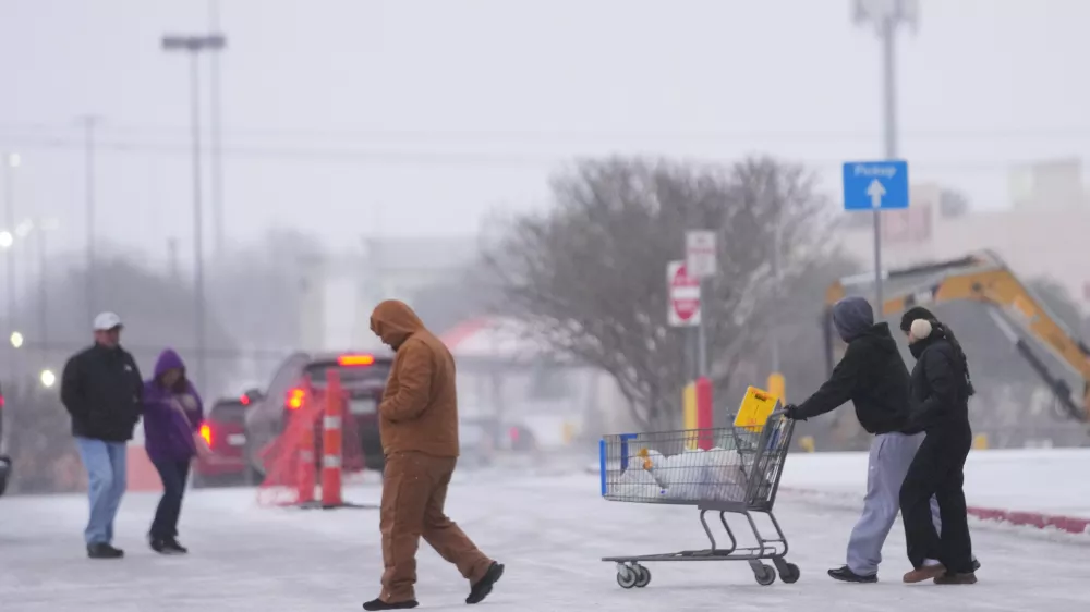 Shoppers brave cold weather as they walk in the parking lot of a store during a winter storm Saturday, Jan. 24, 2026, in Arlington, Texas. (AP Photo/Julio Cortez)