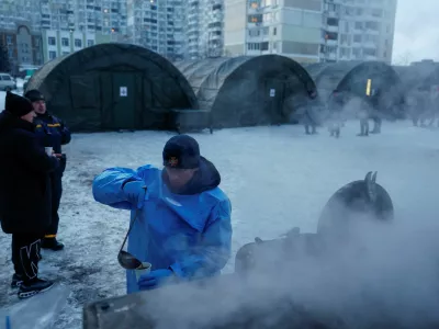 FILE PHOTO: A State Emergency Service employee pours tea into a cup in front of tents of a government-run humanitarian aid point, where residents can warm up, charge their devices, get hot drinks and psychological support, installed next to apartment buildings during a power blackout after critical civil infrastructure was hit by recent Russian missile and drone strikes, amid Russia's attack on Ukraine, in Kyiv, Ukraine, January 25, 2026. REUTERS/Valentyn Ogirenko/File Photo