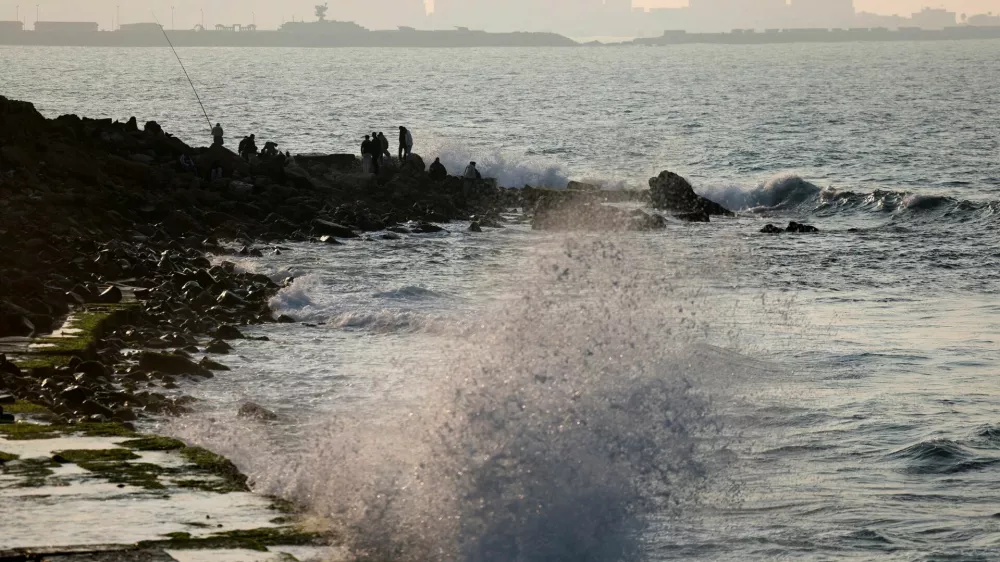 Waves crash against the rocks near where people sit on the shore of the Mediterranean Sea, in the port city of Alexandria, Egypt, January 25, 2026. REUTERS/Mohamed Abd El Ghany