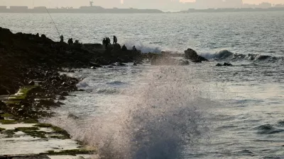 Waves crash against the rocks near where people sit on the shore of the Mediterranean Sea, in the port city of Alexandria, Egypt, January 25, 2026. REUTERS/Mohamed Abd El Ghany