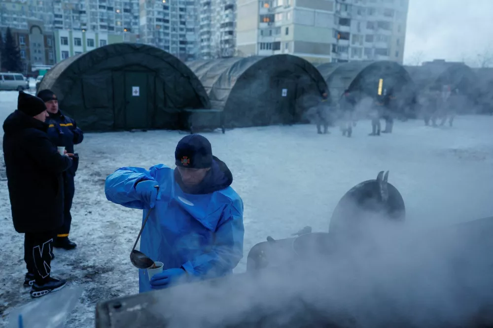 FILE PHOTO: A State Emergency Service employee pours tea into a cup in front of tents of a government-run humanitarian aid point, where residents can warm up, charge their devices, get hot drinks and psychological support, installed next to apartment buildings during a power blackout after critical civil infrastructure was hit by recent Russian missile and drone strikes, amid Russia's attack on Ukraine, in Kyiv, Ukraine, January 25, 2026. REUTERS/Valentyn Ogirenko/File Photo