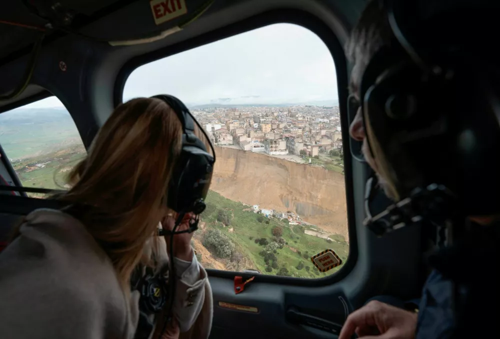Italian Prime Minister Giorgia Meloni looks out the window as she flies over the Sicilian town of Niscemi, parts of which have been left standing on the edge of a cliff after a landslide triggered by a storm, Italy, January 28, 2026. Italian Government Press Office/Handout via REUTERS ATTENTION EDITORS THIS IMAGE HAS BEEN SUPPLIED BY A THIRD PARTY. NO ARCHIVE. NO RESALE.