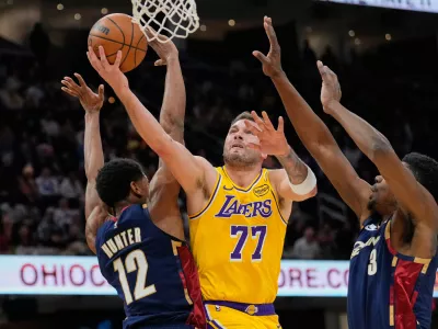 Los Angeles Lakers guard Luka Doncic shoots between Cleveland Cavaliers forward De'andre Hunter (12) and center Thomas Bryant (3) in the second half of an NBA basketball game in Cleveland, Wednesday, Jan. 28, 2026. (AP Photo/Sue Ogrocki)