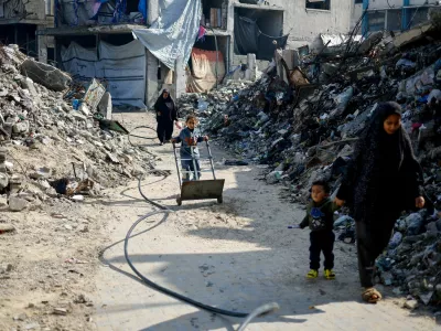 FILE PHOTO: Palestinians walk past the rubble of residential buildings destroyed during the war, in Jabalia, northern Gaza Strip, January 6, 2026. REUTERS/Mahmoud Issa/File Photo