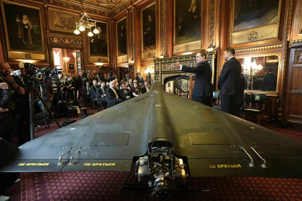 Britain's former security minister Tom Tugendhat, second right, and Polish foreign minister Radek Sikorski speak in front of a downed Russian's army Shahed-136 attack drone, during a press conference organised by United Against Nuclear Iran (UANI), in Speaker's Court at the House of Commons, Westminster, London, Tuesday, Oct. 14, 2025. (Stefan Rousseau/PA via AP)