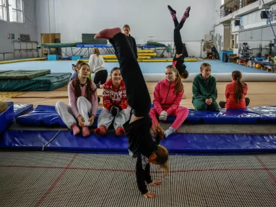 Girls look at their teammate practicing on a trampoline in a gymnastics hall, where the temperature does not exceed 5 degrees Celsius (about 41 degrees Fahrenheit), as they are dressed in winter socks, gloves and multiple layers of clothing, while the city faces power outages and problems with heat after recent Russian missile and drone strikes on critical infrastructure, amid Russia's attack on Ukraine, in Kyiv, Ukraine, January 29, 2026. REUTERS/Alina Smutko