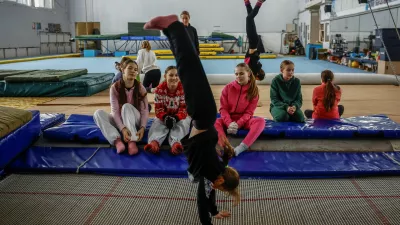 Girls look at their teammate practicing on a trampoline in a gymnastics hall, where the temperature does not exceed 5 degrees Celsius (about 41 degrees Fahrenheit), as they are dressed in winter socks, gloves and multiple layers of clothing, while the city faces power outages and problems with heat after recent Russian missile and drone strikes on critical infrastructure, amid Russia's attack on Ukraine, in Kyiv, Ukraine, January 29, 2026. REUTERS/Alina Smutko