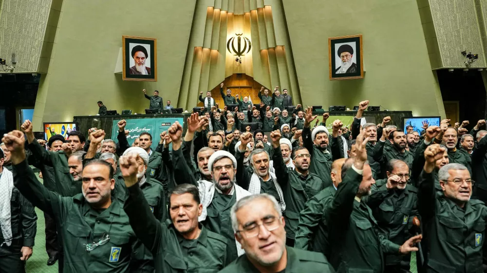 In this handout photo released by the Islamic Consultative Assembly News Agency (ICANA) Iranian lawmakers chant slogans as they wear the Revolutionary Guard's uniform in a session of parliament, in Tehran, Iran, Sunday, Feb. 1, 2026. (Hamed Malekpour/ICANA via AP)