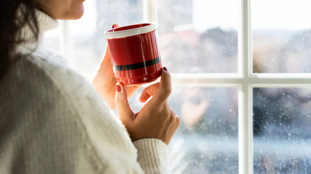 A girl drinks a cup of coffee on a cold day. Relaxed day at home in Christmas time. / Foto: Rolart Studio, Getty Images