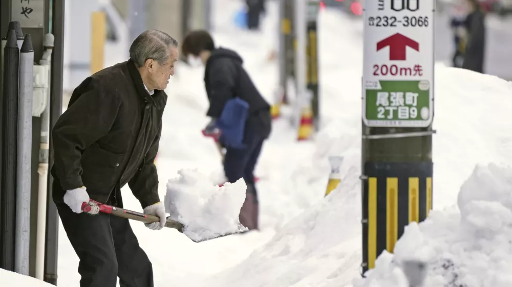 Residents shovel snow off a sidewalk in Kanazawa, Ishikawa prefecture, central Japan, on Dec. 24, 2022. (Kyodo News via AP)