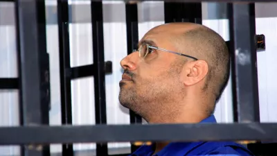 FILE PHOTO: Saif al-Islam Gaddafi, son of late Libyan leader Muammar Gaddafi, attends a hearing behind bars in a courtroom in Zintan May 25, 2014. REUTERS/Stringer/File Photo