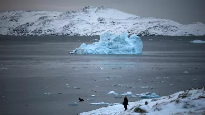 A person walks on the shore as a small iceberg floats in the sea near Nuuk, Greenland, February 4, 2026. REUTERS/Stoyan Nenov
