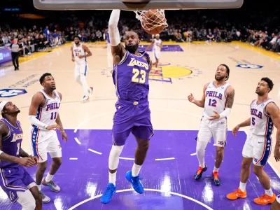 Los Angeles Lakers forward LeBron James, center, dunks as forward Jarred Vanderbilt, left, watches along with Philadelphia 76ers forward Justin Edwards, second from left, forward Trendon Watford, second from right, and guard Quentin Grimes during the first half of an NBA basketball game Thursday, Feb. 5, 2026, in Los Angeles. (AP Photo/Mark J. Terrill)