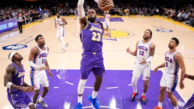 Los Angeles Lakers forward LeBron James, center, dunks as forward Jarred Vanderbilt, left, watches along with Philadelphia 76ers forward Justin Edwards, second from left, forward Trendon Watford, second from right, and guard Quentin Grimes during the first half of an NBA basketball game Thursday, Feb. 5, 2026, in Los Angeles. (AP Photo/Mark J. Terrill)