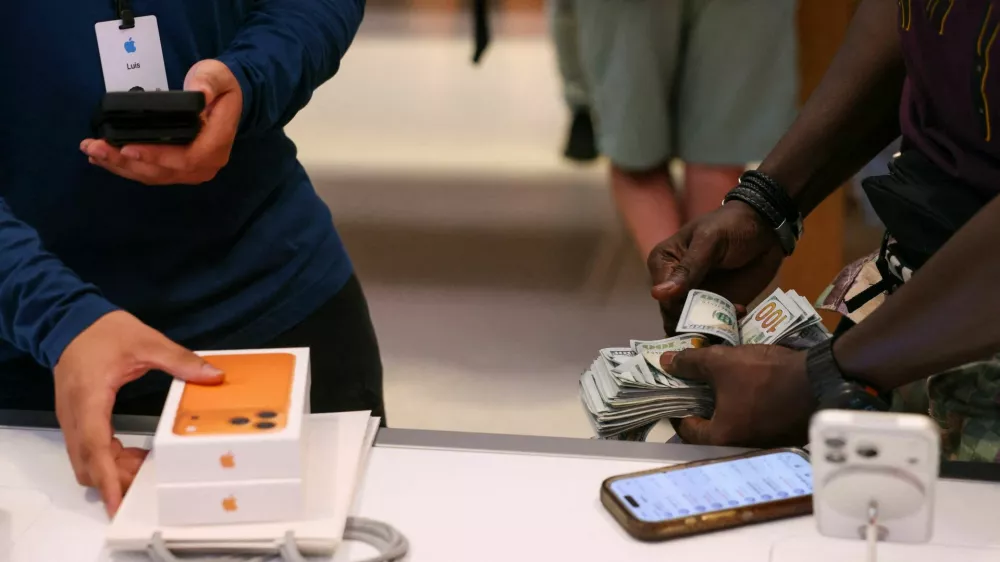 FILE PHOTO: A man purchases an iPhone 17 series with cash at the Apple Store in New York City, U.S., September 19, 2025. REUTERS/Shannon Stapleton/File Photo