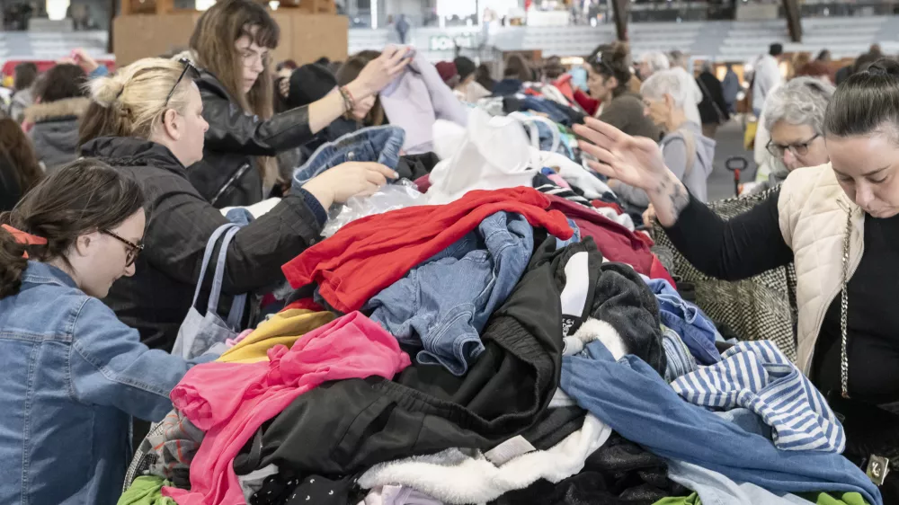 France, 2025-04-04. Emmaus flea market in Poitiers. Sitting on either side of a large table strewn with second-hand clothes, people frantically search for those that might suit them. The hyper-consumerism of the French means that twice a year, the Emmaus companions organise a big jumble sale to get rid of their stocks of unsold goods. You ll find mountains of second-hand clothes, books, furniture and crockery at low prices. Photograph by Jean-Francois Fort / Hans Lucas.France, 2025-04-04. Braderie Emmaus a Poitiers. Installees part et d autres d une grande table jonchee de vetements d occasions, des personnes recherchent avec attention ceux qui pourraient leur convenir. L hyper consommation des Francais fait que 2 fois par ans les compagnons d Emmaus organisent une grande braderie pour se debarrasser de leurs stocks d invendus. On y trouve de veritables montagnes de vetements, de livres, de meubles, de vaisselle, d occasion et a petit prix. Photographie de Jean-Francois Fort / Hans Lucas.