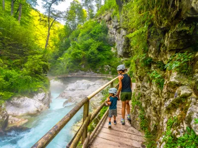 Mother and child walking on wooden path exploring vintgar gorge near bled, enjoying summer vacation in beautiful nature of slovenia