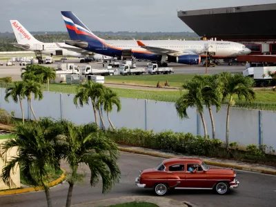 FILE PHOTO: The Aeroflot aircraft for the SU150 Moscow-Havana flight (R) is seen as a taxi drives out of a parking lot at Havana's Jose Marti International Airport June 24, 2013. REUTERS/Desmond Boylan/File Photo/File Photo