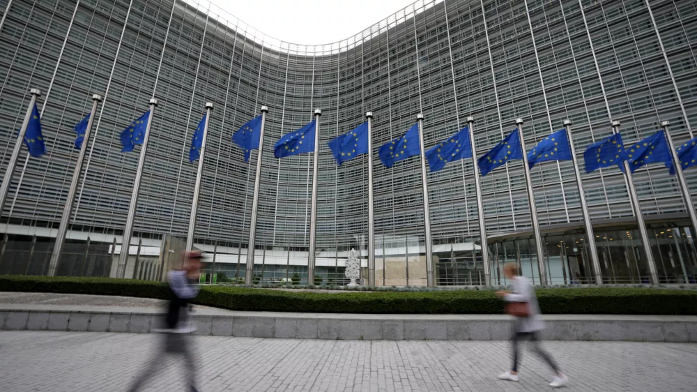 FILE - European Union flags wave in the wind as pedestrians walk by EU headquarters in Brussels, on Sept. 20, 2023. The European Union's powerful Commission announced on Thursday that it will start releasing billions of euros to Poland after the funds were frozen over the previous government's policies that the bloc said amounted to widespread backsliding of fundamental democratic principles. (AP Photo/Virginia Mayo, File)