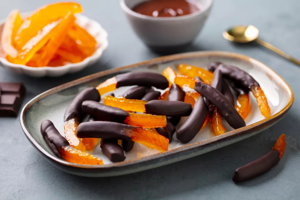 Chocolate Covered Candied Orange Peel. Scorze Di Arancia Al Cioccolato. Grey background. Close up. / Foto: Annapustynnikova
