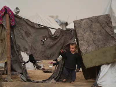Palestinian child looks on as he stands next to a tent at a makeshift camp for displaced people during a dust storm in Zawaida, in the central Gaza Strip, Saturday, Feb. 14, 2026. (AP Photo/Abdel Kareem Hana)