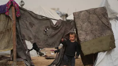 Palestinian child looks on as he stands next to a tent at a makeshift camp for displaced people during a dust storm in Zawaida, in the central Gaza Strip, Saturday, Feb. 14, 2026. (AP Photo/Abdel Kareem Hana)