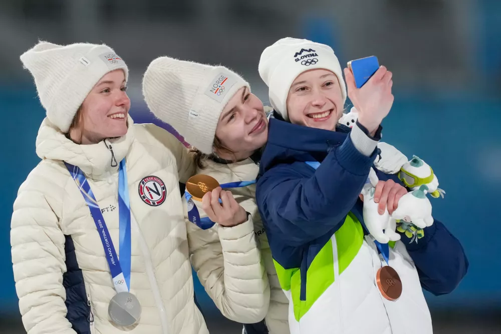 Gold medalist Anna Odine Stroem, of Norway, celebrates on the podium flanked by silver medalist Eirin Maria Kvandal, also of Norway, and bronze medalist Nika Prevc, of Slovenia, right, after the ski jumping women's large hill individual at the 2026 Winter Olympics, in Predazzo, Italy, Sunday, Feb. 15, 2026. (AP Photo/Evgeniy Maloletka)