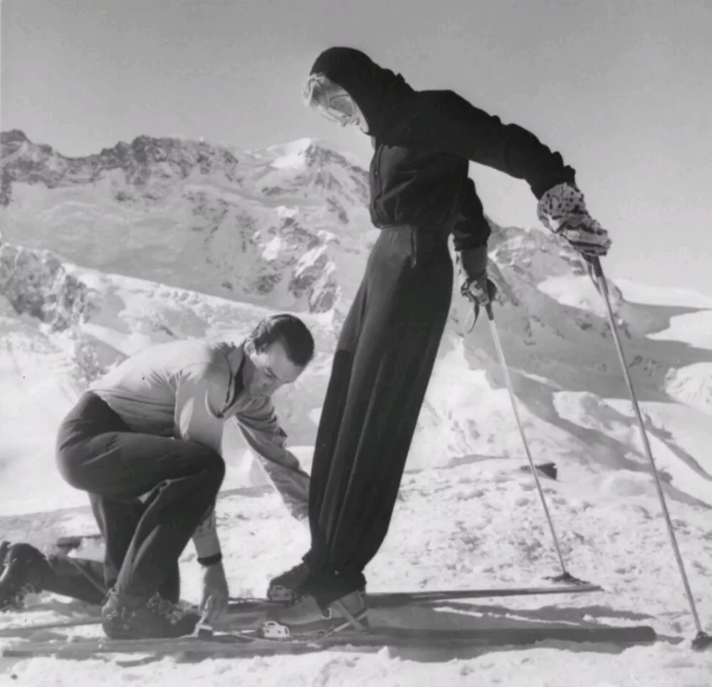 Markiz Emilio Pucci pripenja smučko gospe Poppi de Salis, ki nosi smučarsko oblačilo Pucci; Zermatt, 1947. Harper's Bazaar, december 1948. &copy; Emilio Pucci.