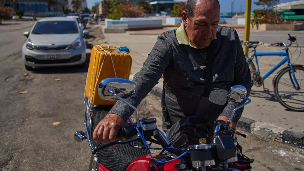 Retiree Jorge Reyes pushes his motorcycle to refuel as it's his turn in line at a gasoline station in Havana, Cuba, Monday, Feb. 16, 2026. (AP Photo/Ramon Espinosa)
