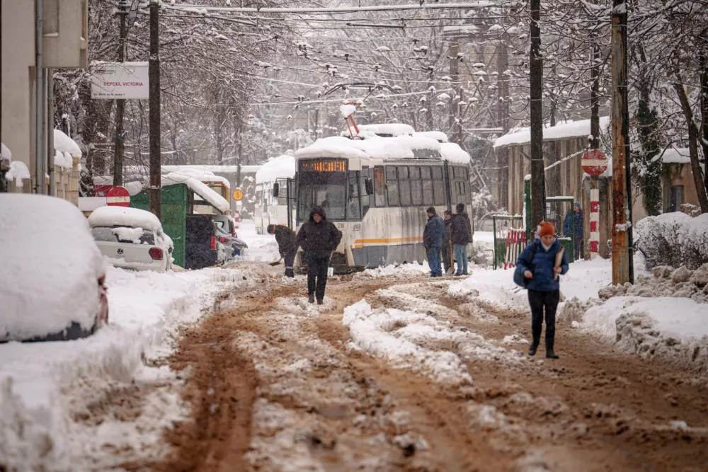 A man shovels snow from the tracks of a tram after a blizzard in Bucharest, Romania, Wednesday, Feb. 18, 2026. (AP Photo/Vadim Ghirda)