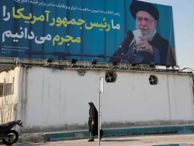 A woman walks past a billboard with an image of Iranian Supreme Leader Ayatollah Ali Khamenei with a quotation of him which says: "We recognise the President of America as a criminal," in Tehran, Iran, Tuesday, Feb. 17, 2026. (AP Photo/Vahid Salemi)